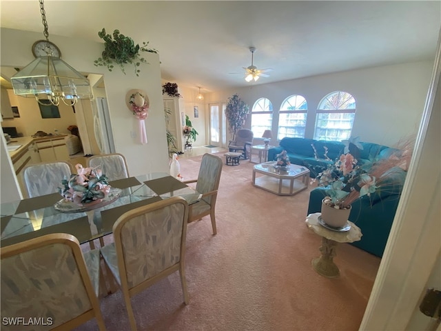 carpeted dining room with ceiling fan with notable chandelier