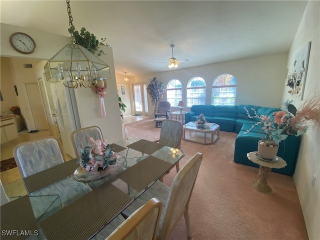 carpeted dining space featuring ceiling fan with notable chandelier