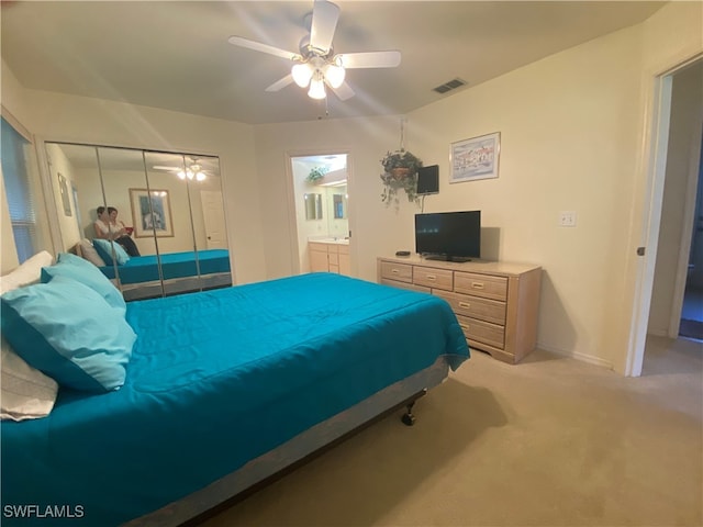 carpeted bedroom with a closet, ensuite bath, and ceiling fan