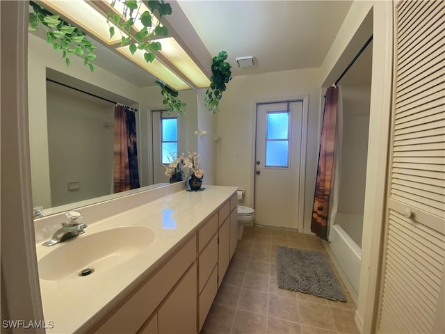 full bathroom with a skylight, vanity, tile patterned flooring, shower / bath combo with shower curtain, and toilet