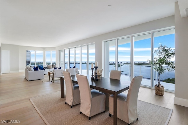 dining area featuring light wood-type flooring and a water view