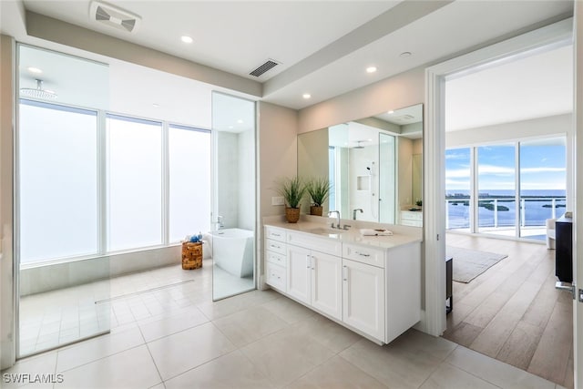 bathroom with vanity, a water view, a tub, and tile patterned floors