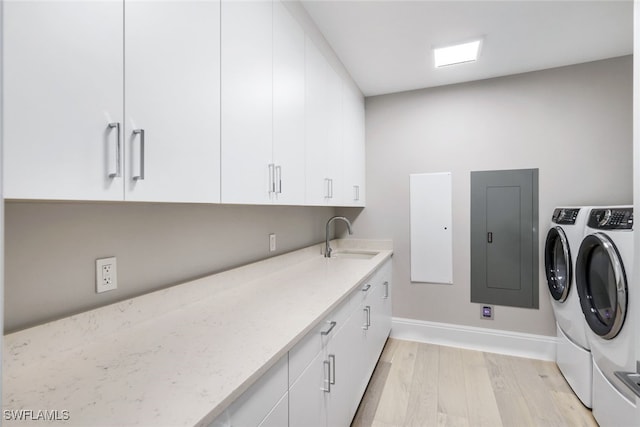 laundry area with washer and clothes dryer, light hardwood / wood-style floors, sink, and cabinets