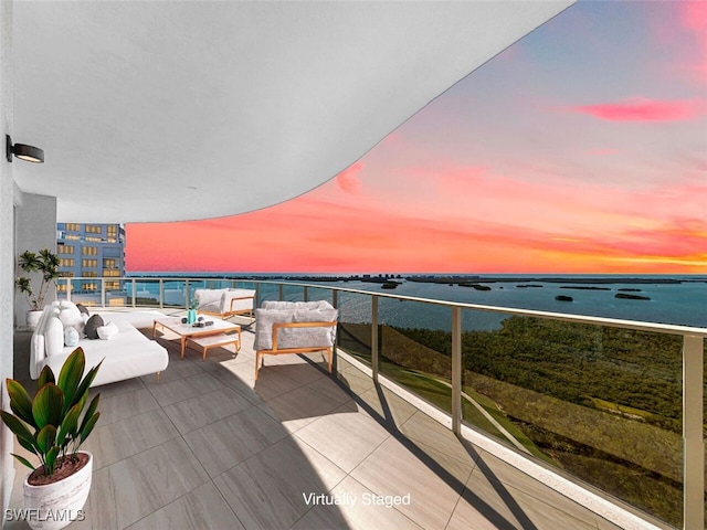 balcony at dusk with a water view and an outdoor living space