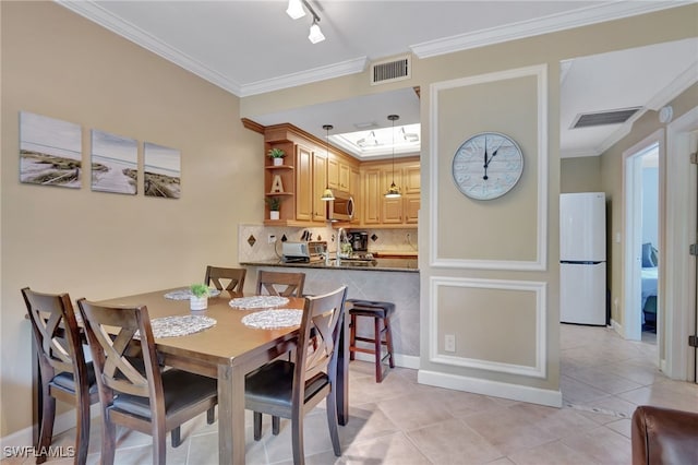 dining space featuring light tile patterned floors, crown molding, and track lighting