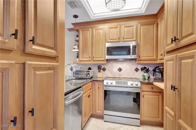 kitchen featuring backsplash, sink, light tile patterned floors, appliances with stainless steel finishes, and decorative light fixtures