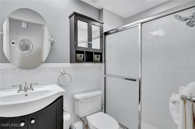 bathroom with an enclosed shower, vanity, toilet, and tile walls