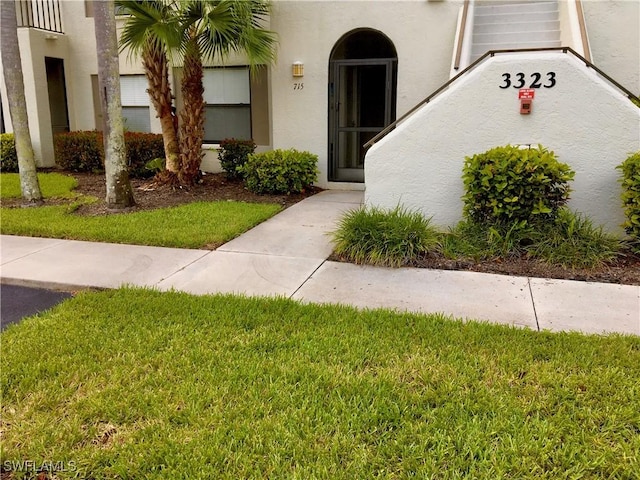 3323 Olympic Dr Unit 715, Naples, FL 34105 - doorway to property with a yard and stucco siding