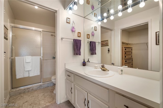 bathroom with a shower with door, vanity, and toilet