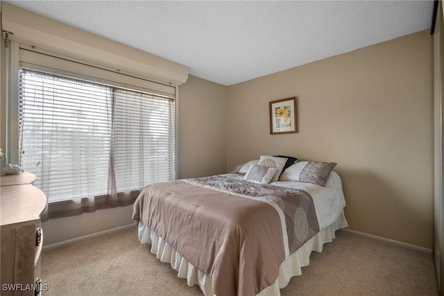 bedroom featuring light carpet, multiple windows, and a textured ceiling