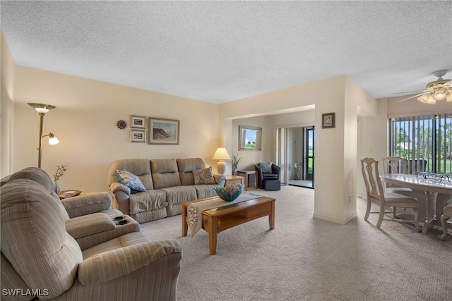 living room featuring ceiling fan, light colored carpet, and a textured ceiling