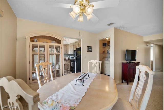 dining room featuring a textured ceiling, ceiling fan, washer / clothes dryer, and light colored carpet