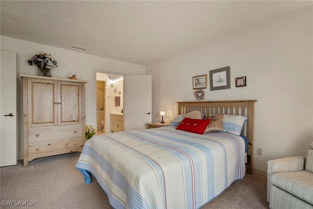 carpeted bedroom featuring a textured ceiling and ensuite bathroom