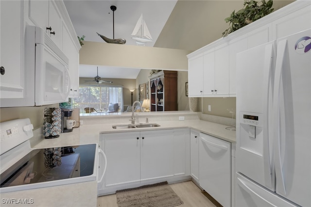 kitchen featuring sink, vaulted ceiling, white appliances, white cabinets, and light wood-type flooring