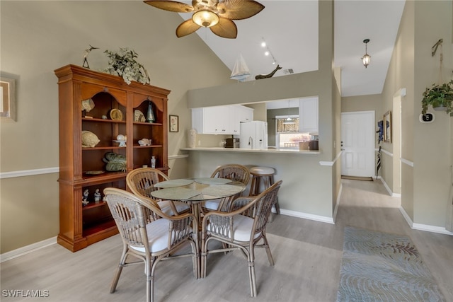 dining area with ceiling fan, light wood-type flooring, and high vaulted ceiling