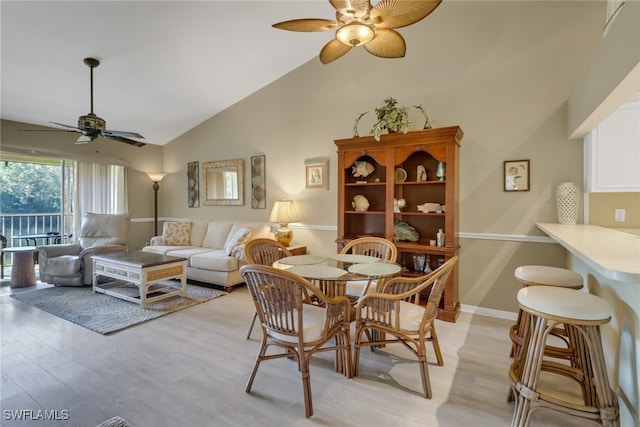 dining area with light wood-type flooring, high vaulted ceiling, and ceiling fan