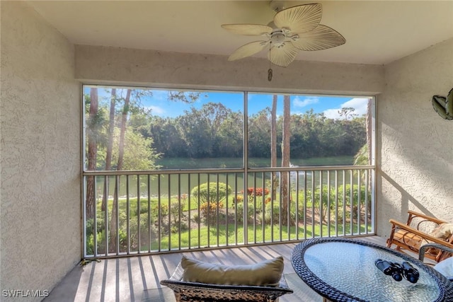 sunroom with a wealth of natural light, a water view, and ceiling fan