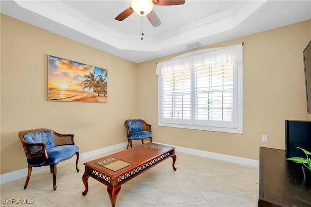 living area featuring crown molding, ceiling fan, and a raised ceiling