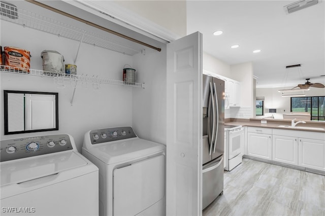 laundry area featuring sink, washer and clothes dryer, light hardwood / wood-style floors, and ceiling fan