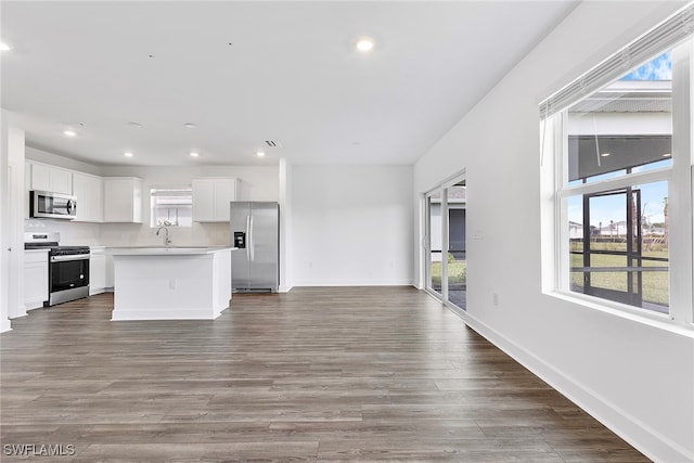 kitchen featuring white cabinets, appliances with stainless steel finishes, a center island, and hardwood / wood-style flooring