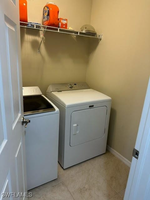 laundry area with washing machine and clothes dryer and light tile patterned floors