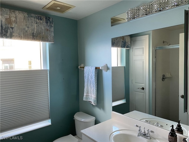 bathroom featuring an enclosed shower, a wealth of natural light, vanity, and toilet