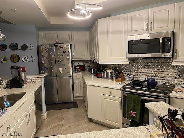 kitchen featuring stainless steel appliances, hanging light fixtures, sink, tasteful backsplash, and white cabinetry