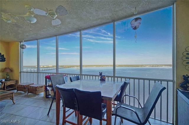 sunroom featuring a water view, plenty of natural light, and ceiling fan