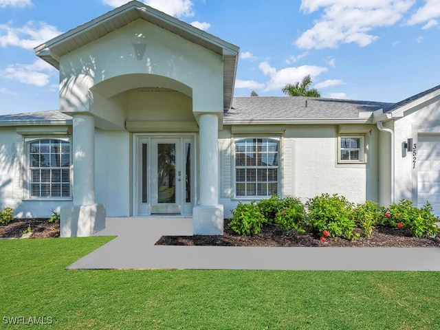 view of exterior entry featuring a garage and a lawn