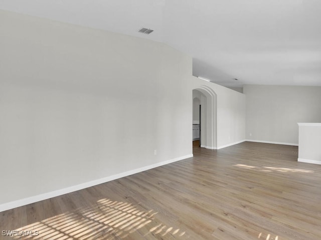 empty room featuring wood-type flooring and vaulted ceiling