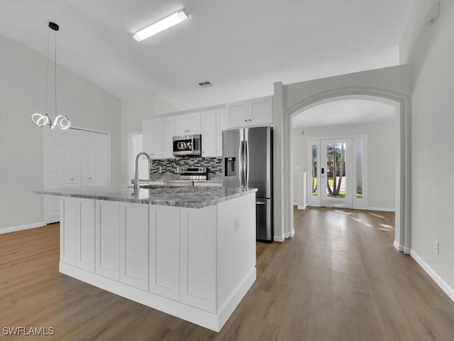 kitchen with light stone countertops, appliances with stainless steel finishes, an island with sink, and white cabinets