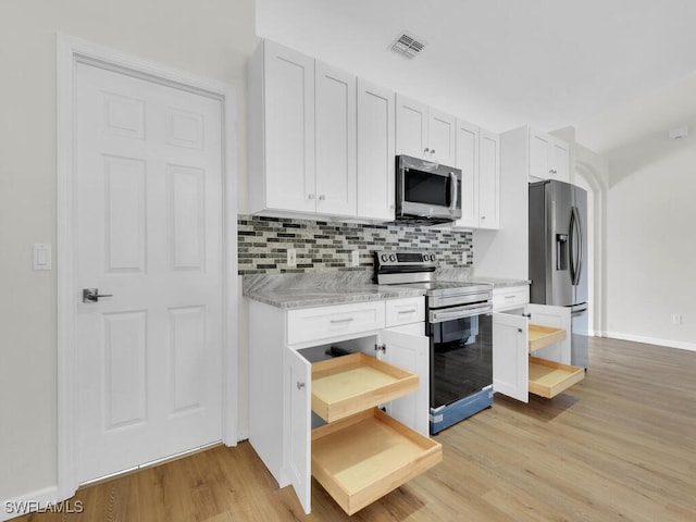 kitchen with backsplash, white cabinetry, light stone countertops, light hardwood / wood-style floors, and stainless steel appliances