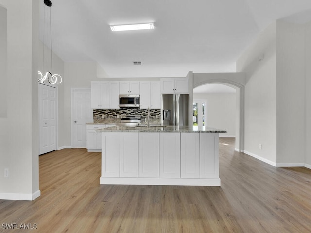 kitchen featuring light hardwood / wood-style flooring, hanging light fixtures, white cabinetry, appliances with stainless steel finishes, and light stone counters