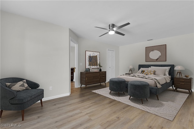 bedroom with a closet, light hardwood / wood-style floors, and ceiling fan