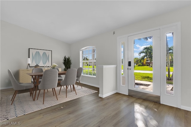 dining area with hardwood / wood-style floors, vaulted ceiling, and a healthy amount of sunlight