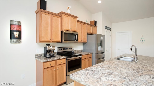 kitchen with light stone counters, sink, stainless steel appliances, and vaulted ceiling