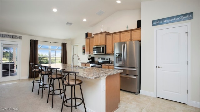 kitchen featuring sink, stainless steel appliances, a kitchen breakfast bar, lofted ceiling, and a kitchen island with sink