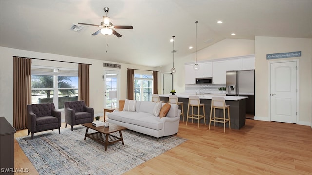 living room with ceiling fan, light hardwood / wood-style floors, lofted ceiling, and a wealth of natural light