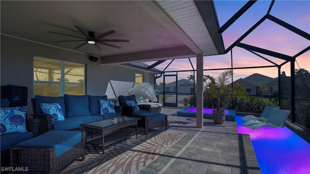 patio terrace at dusk featuring an outdoor hangout area, glass enclosure, and ceiling fan