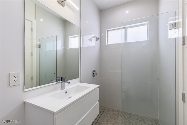 bathroom with tiled shower and vanity