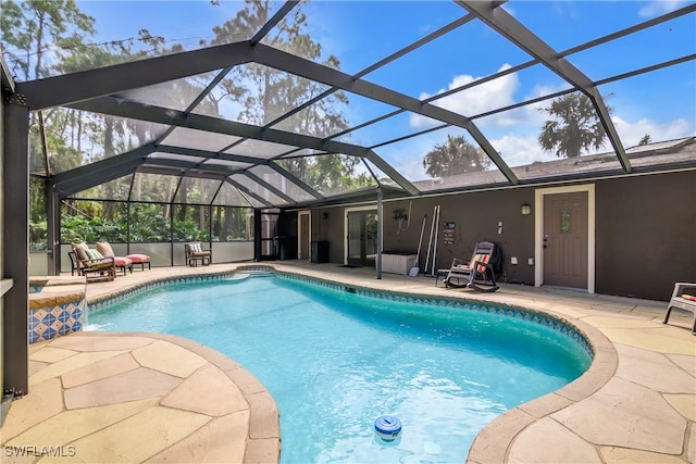 view of swimming pool featuring glass enclosure and a patio area