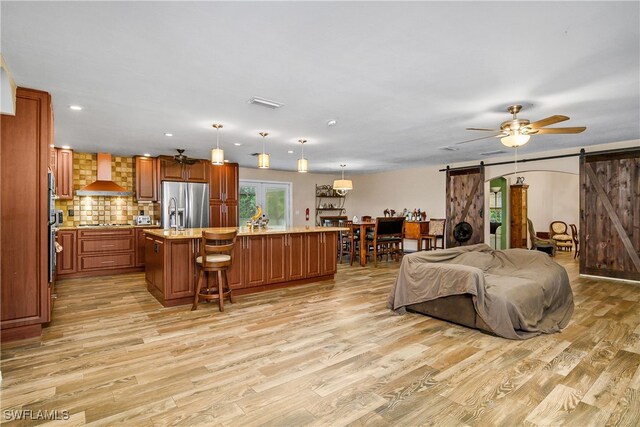 living room with ceiling fan, light hardwood / wood-style flooring, and a barn door