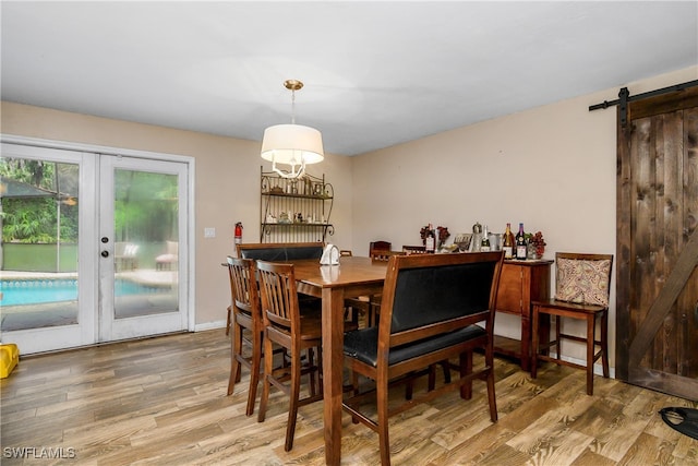 dining space featuring wood-type flooring, french doors, and a barn door