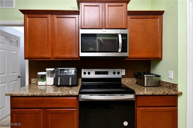 kitchen with appliances with stainless steel finishes, tile patterned floors, and stone countertops