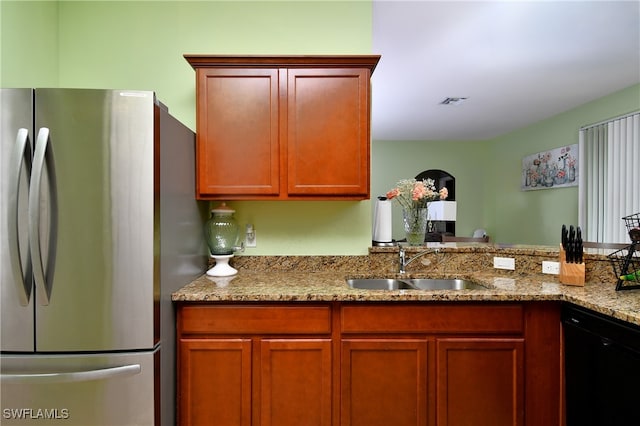 kitchen featuring dishwasher, light stone countertops, stainless steel fridge, and sink