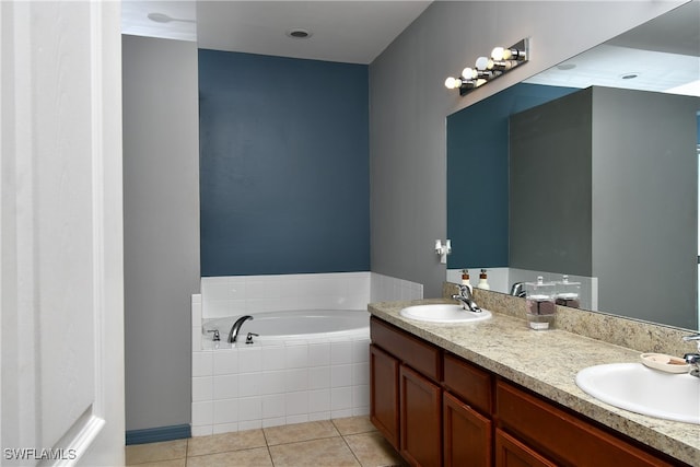 bathroom featuring tiled tub, vanity, and tile patterned flooring