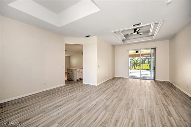 spare room with a raised ceiling and light hardwood / wood-style flooring