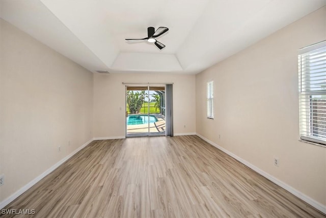 spare room with ceiling fan, a raised ceiling, and light hardwood / wood-style flooring