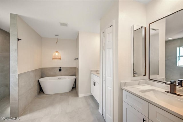 bathroom with vanity, a tub to relax in, and tile walls