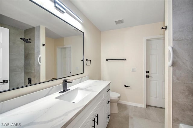 bathroom with tile patterned flooring, vanity, toilet, and a tile shower